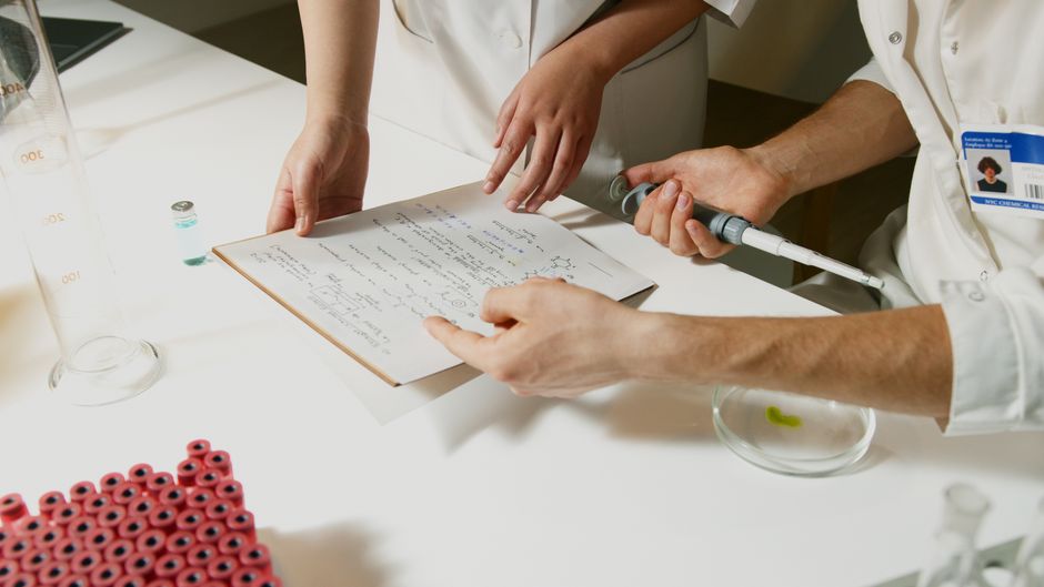 Researchers in a lab engaging in collaborative scientific research with documents and equipment.